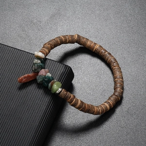 Macro shot of bohemian coconut shell beads with colorful natural raw stones on a dark base