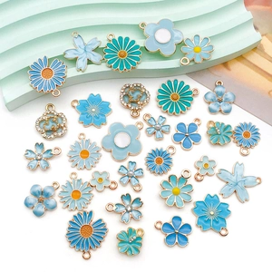 Detailierte Anordnung von blauen Emaille-Gänseblümchen und Blumenanhängern für DIY-Schmuck