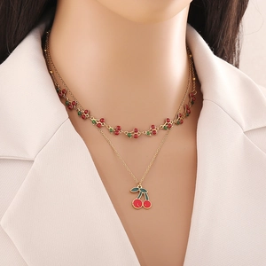 Gros plan d'un collier doré double épaisseur avec pendentifs cerises rouges sur un mannequin