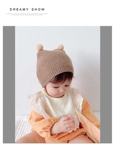 Close-up of brown knit baby hat featuring cute double pom-poms and soft ear protection