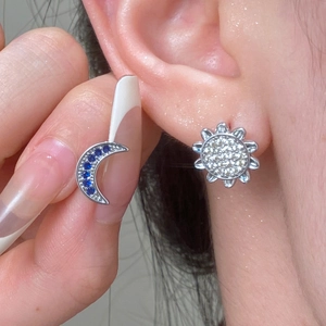 Close-up of vintage silver moon and sun earrings with blue and clear gemstones