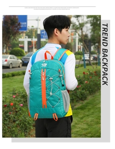 Outdoor turquoise backpack with orange details and side mesh pocket worn by a model
