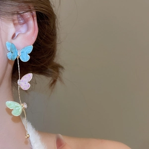 Detailed close-up of colorful butterfly tassel earrings with blue pink and green charms