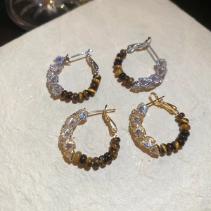 Detailed view of 18k gold and silver plated earrings with zircons and tiger eye stones