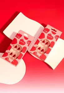 Detail of soft gel tips packaging with heart pattern and nude red Valentine's nail art