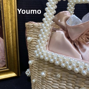 Detail of handmade straw bag with pearl embellishments and pink satin drawstring liner