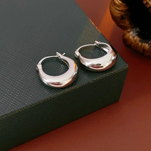 Close-up of polished silver U-shaped metal earrings on a dark textured display box