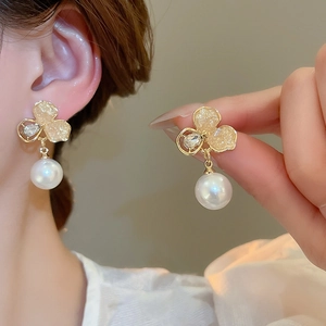 Gros plan de boucles d'oreilles fleur élégantes avec perles blanches et cristaux