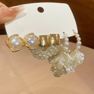Detailed view of pearl flower earrings and square stud set on a white display card