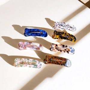 Detailed top view of assorted acetate duckbill hair clips with marble patterns and long shadows