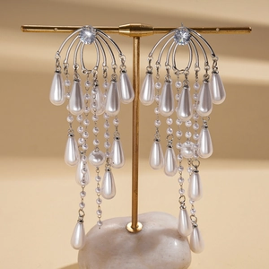 Close-up of silver drop fringe earrings with zircon and pearls on a display stand