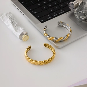 Minimalist 18K gold stainless steel twisted rope open bangles on a modern desk setup