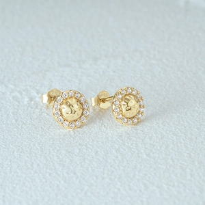 Detail of gold hammer-textured stud earrings with sparkling cubic zirconia halo