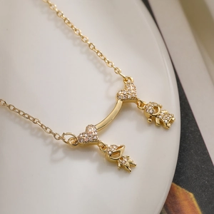 Gold plated copper necklace with zircon hearts and boy-girl pendants on a curved bar