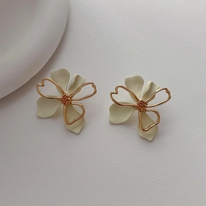 Minimalist hollow metal flower earrings with cream petals and gold trim on white background