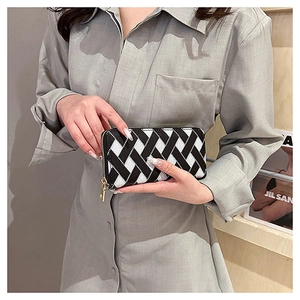 Close-up of long wallet with black and white woven pattern and gold key pendant zipper
