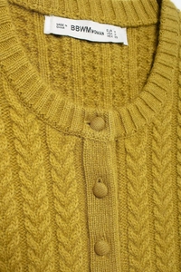 Close-up of mustard knit cardigan showing textured cable pattern and neckline details