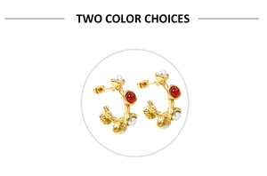Detail of gold hoops with irregular texture featuring white pearls and red gemstones