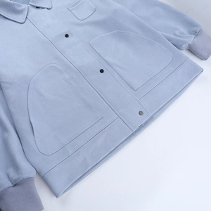 Close-up of light blue polo jacket featuring rib-knit cuffs and large utility pockets