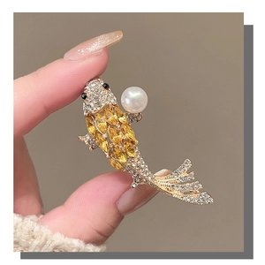 Detailed close-up of a golden koi fish brooch with crystals and a white pearl accent