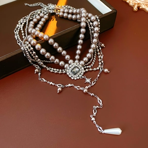 Macro detail of luxury multilayer necklace with grey pearls and crystal square pendant