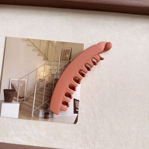 Clay pink matte banana hair clip for thick hair shown in a lifestyle scene setting