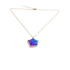 Macro detail of star pendant with blue-purple gradient and gold stainless steel chain
