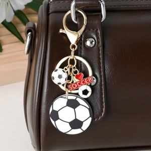 Golden soccer keychain featuring heart charm and red soccer tag hanging on brown bag