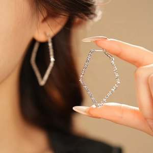 Detailed view of silver-tone geometric rhombus hoop earring with textured metal surface