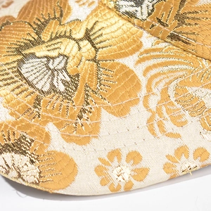 Detailed close-up of golden floral jacquard fabric on a Chinese style baseball cap