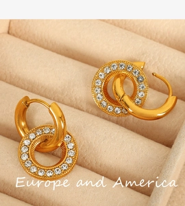 Macro detail of gold geometric double-hoop earrings with white rhinestones in a jewelry box
