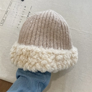 Detail of beige chunky knit beanie with plush faux fur trim on brim for winter warmth