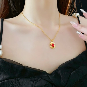 Close-up of a vintage oval gold necklace with a red gemstone on a woman's neck