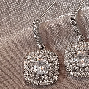 Macro shot of silver cushion-cut drop earrings with double halo zircon detailing