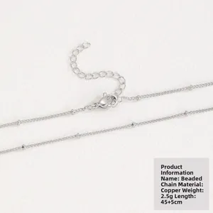 Macro detail of silver-toned copper bead chain with lobster clasp and extension link