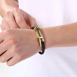Detail of a men's braided leather bracelet with a golden nail-head clasp.