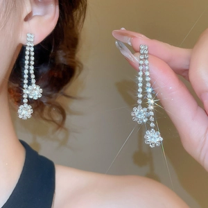 Close-up of silver long tassel earrings with sparkling zircon flower detail on model