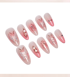 Detailed view of pink blush gradient press-on nails with glitter butterfly patterns