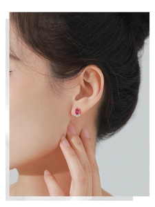 Detailed view of an S925 silver earring with an oval ruby and white diamonds on a model
