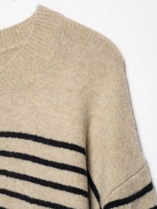 Détail d'un pull en maille beige avec rayures noires et col rond texturé de haute qualité