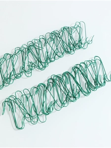 Detailed view of green S-shaped metal hooks for Christmas tree ornaments on white background