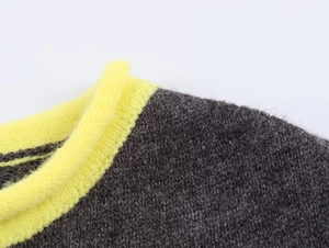 Detail of grey and yellow contrast knit sweater showing ribbed crewneck and soft wool blend