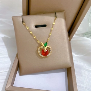 Macro view of gold apple pendant with red crystal and sparkling pavé stones in jewelry box