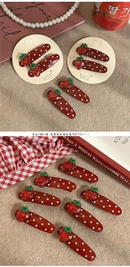 Detailed view of red strawberry polka dot hair clips set on a beige display card