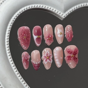Detailed view of 3D almond press-on nails with handmade flowers, pearls and pink marble patterns