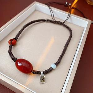Macro detail of agate stone necklace with face relief pendant in a beige gift box