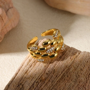 Close-up of golden adjustable ring with textured scales and sparkling white zircon accents
