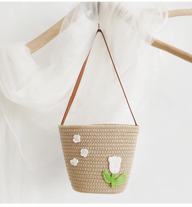 Close-up of hand-woven straw bag with white tulip embroidery and brown leather strap