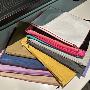 Assorted colorful nylon zipper organizer pouches in a minimalist stack arrangement