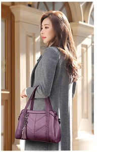 Detailed view of dark purple leather handbag with V-shaped quilting and tassel charm